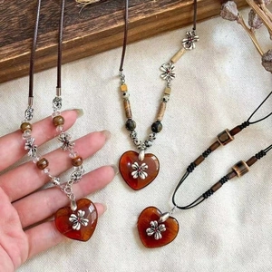 Detail of vintage heart ceramic necklaces with floral metal accents and beaded cords