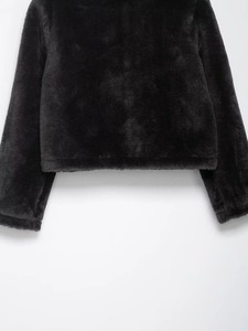 Gros plan détaillé de la veste noire en fausse fourrure montrant la texture et les poignets
