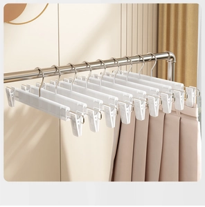 Close-up of white adjustable plastic pants hangers with metal hooks in a home setting
