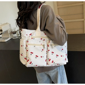 Detail of cherry print tote bag featuring spacious front pockets and canvas texture
