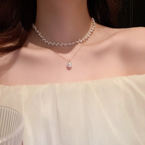 Gros plan du collier double rang avec perles et chaîne dorée sur le cou du modèle