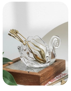 Detail of elegant swan glass base with embossed gold spoons on vintage tray