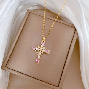 Detailed shot of pearl cross necklace with pink stones on brown jewelry box and silk