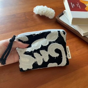 Detailed close-up of bohemian linen coin purse with white botanical floral embroidery
