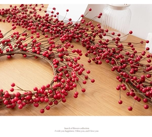 Close-up of vibrant red artificial berry vines on a rustic light wood background