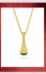 Detail of gold necklace pendant with white diamonds and a blue gemstone on red background