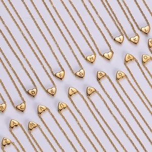 Golden 18K gold-plated heart pendant necklaces with A-Z letters on a gray background