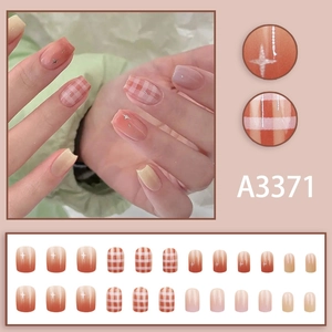 Short square press-on nails with orange pink gradient, plaid pattern, and silver stars