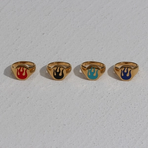 Detail of four 18K gold plated stainless steel rings with colorful enamel flame patterns