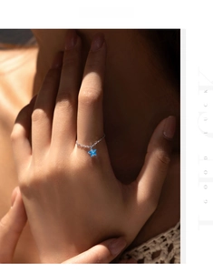 Detail of S925 sterling silver chain ring featuring a dangling blue star charm on finger