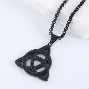 Détail d'un pendentif Triquetra celtique en acier inoxydable noir sur une pierre claire