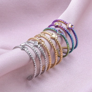 Detailed view of a 7-piece heart-shaped stainless steel ring set on pink silk fabric