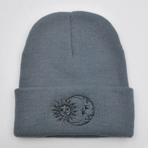 Close-up of sun and moon embroidery on a grey knitted beanie for autumn and winter