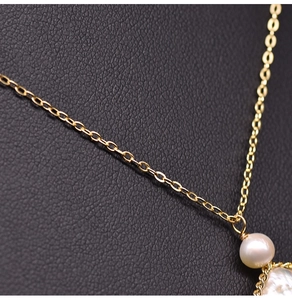 Macro detail of natural freshwater baroque pearl pendant with delicate golden chain link