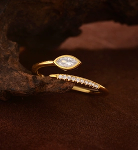 Macro shot of gold snake-shaped ring with marquise zircon on textured wood branch