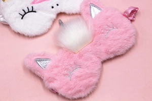 Detailed view of pink and white plush unicorn sleep masks with soft faux fur texture