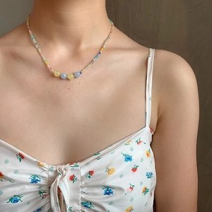 Colorful rainbow seed bead necklace with cat-eye stones worn by a model in natural light