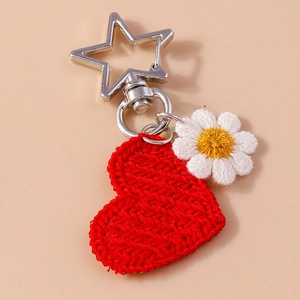Detail of a red knitted heart and embroidered white daisy on a star-shaped metal keyring