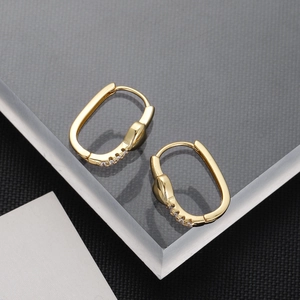 Macro detail of 18K gold plated oval hoop earrings featuring micro-pave zircon crystals