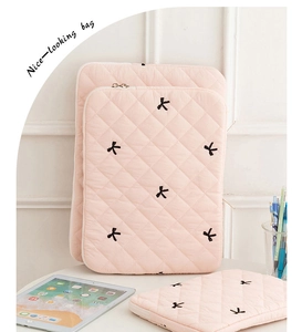 Detailed view of pink quilted tablet sleeves featuring elegant black bow embroidery