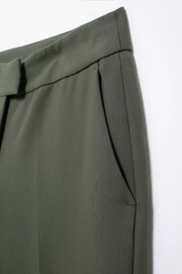 Détail du pantalon vert foncé montrant la poche latérale et la texture du tissu