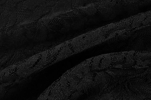 Macro view of delicate black floral lace fabric with intricate mesh cutout details
