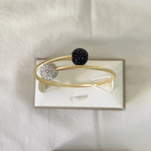 Détail d'un bracelet torsadé en or 18k avec embouts sphériques sertis de cristaux