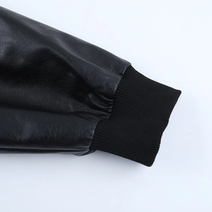 Close-up of black leather jacket cuffs with ribbed knit texture and premium stitching