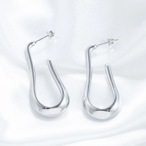 Polished silver U-shaped geometric earrings on white silk background with minimalist design