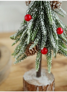 Close-up of a 24cm mini Christmas tree with snow, red berries, and natural wood base