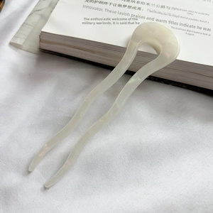 Macro view of wave-shaped cream acetate U-shaped hair pin with a pearlescent finish