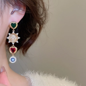 Detail shot of vintage heart and evil eye charms on asymmetric dangle earrings for women