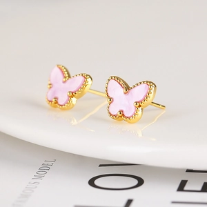 Macro shot of pink butterfly stud earrings with gold beaded edges on a white plate