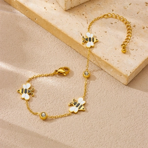 Gold plated stainless steel bee charm bracelet with zircon accents on marble background