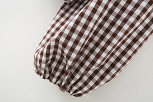 Close-up of brown gingham long sleeve shirt with elastic cuff and soft fabric texture