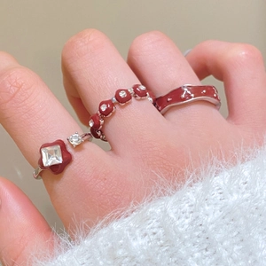 Detailed view of three-piece red enamel and silver alloy rings set on finger