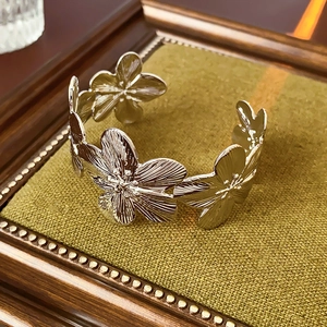 Gros plan d'un bracelet ouvert fleuri argenté avec détails brossés sur velours vert