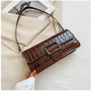 Detail of dark brown crocodile texture leather baguette bag with polished square buckle