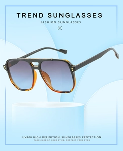 Detail of pilot sunglasses featuring tortoise frame and UV400 gradient lenses on a stand
