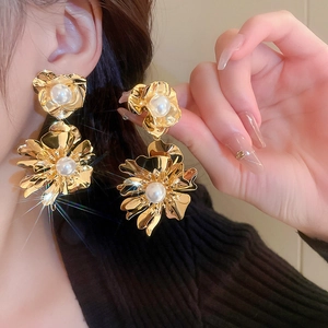 Gros plan de grandes boucles d'oreilles fleur dorées avec perles blanches sur un mannequin