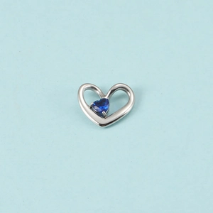 Vue détaillée du pendentif cœur argenté avec un cristal de pierre de naissance bleu