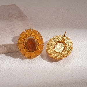 Detail of vintage gold earrings with amber oval stones and yellow beads on stone surface