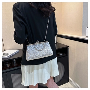 Detail of silver sequin evening bag with metal ring handle and chain strap on model