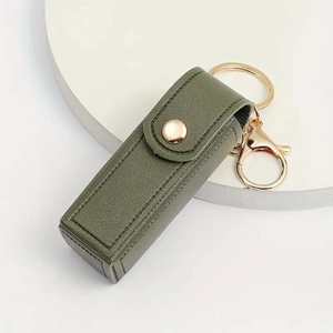 Olive green PU leather lipstick case keychain with gold snap on a white marble base
