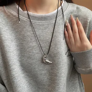 Minimalist silver croissant pendant necklace with black leather cord on a grey sweater