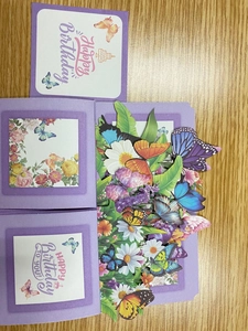 Macro detail of 3D pop-up birthday card with purple butterflies and vibrant floral paper art