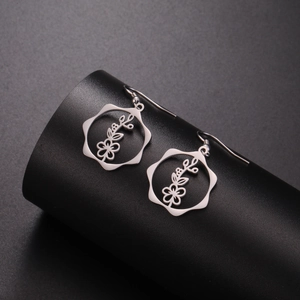 Macro shot of silver stainless steel floral earrings with geometric frames on a black stand