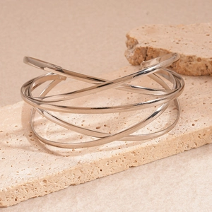 Detail of silver geometric multi-layer open bracelet displayed on beige stone