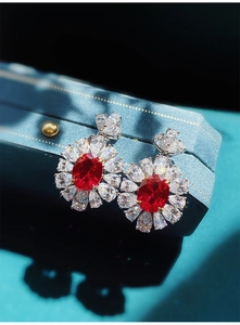 Primo piano di eleganti orecchini a fiore stile rubino con pietre centrali ovali rosse
