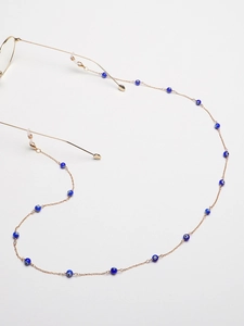 Dettaglio catena per occhiali dorata con perline blu e anelli in gomma regolabili